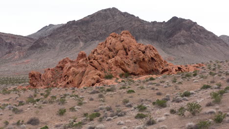 Pull-back-drone-aerial-shot-of-Red-Sandstone-formation-revealing-the-barren-landscape-in-the-back