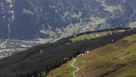 Dolly-Aéreo-Sigue-Al-Parapente-Sobrevolando-Los-Alpes-Del-Valle-De-Grindelwald,-Descenso-Gradual