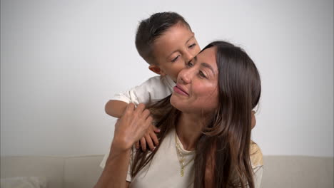 Slow-motion-of-a-nice-handsome-mexican-latin-young-boy-hugging-his-brunette-mother-from-behind-and-kissing-her-looking-to-the-camera