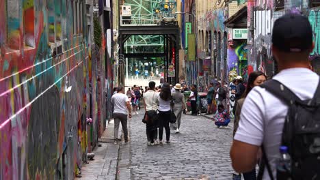 Menschen-Besuchen-Hosier-Lane,-Eine-Beliebte-Kopfsteinpflastergasse-Mit-Einer-Lebendigen-Palette-An-Kunstwandmalereien-Und-Graffiti-An-Den-Wänden,-Eine-Kreative-Kulturelle-Straßenszene-Im-Stadtzentrum-Von-Melbourne