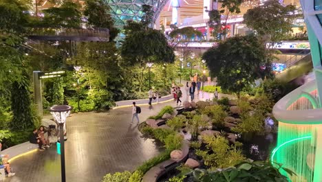 Scenic-view-of-The-Orchard-rainforest-of-trees,-fauna-and-flora-with-people-walking-in-terminal-of-Hamad-International-Airport-in-Doha,-Qatar