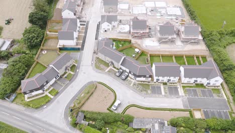 Aerial-view-of-new-homes-being-developed-in-the-countryside,-showcasing-construction-sites-and-green-fields