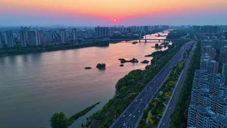 Aerial-establishing-shot-of-Linyi-City-with-the-Binhe-River-in-the-Shandong-Province-during-sunset,-China