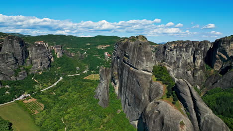 Static-aerial-drone-flight-over-the-nature-of-mountains-and-green-forests-in-between-on-a-warm-day,-copy-space-on-the-blue-sky