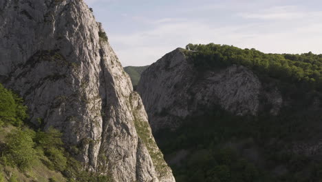 Detail-of-rugged,-rocky-cliff-in-Cheile-Valisoarei-area-of-Romania,-aerial-pedestal-rising-up-mountain,-close-up