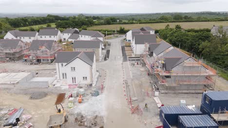 Drone-view-of-a-new-housing-estate-partially-built-in-Devon,-UK,-highlighting-the-construction-progress-and-surrounding-fields