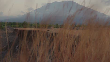 Reveal-shot-Mount-Agung-active-volcano-behind-hay-at-Savana-Tianyar-Bali