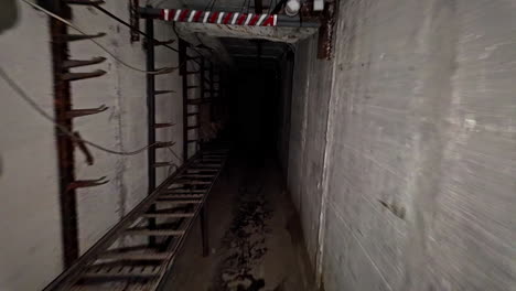 Empty-barren-underground-tunnel-holding-poles-and-long-ladder-railing-along-concrete-wall-edge