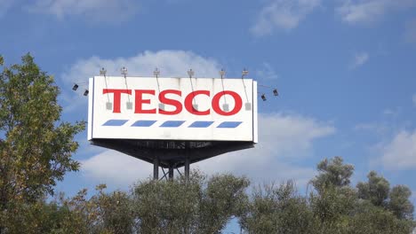 Large-advertisment-banner-tower-of-Tesco-department-store-with-trees-in-slight-breeze