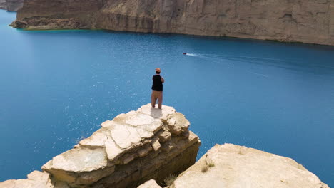 Turista-Masculino-En-Lo-Alto-De-Un-Acantilado-Con-Vistas-Al-Lago-En-El-Parque-Nacional-Band-e-Amir-En-Bamyan,-Afganistán