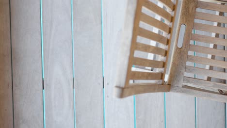 top-down-shot-of-a-wooden-chair-sitting-by-the-poolside-in-a-garden