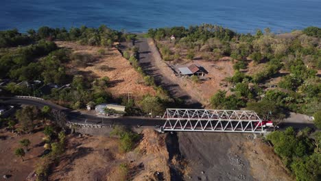 Aerial-shot-of-road-with-bridge-at-countryside-by-the-ocean,-dolly-forward