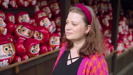 Female-Tourist-Looking-At-Daruma-Dolls-In-Katsuo-ji-Temple-In-Osaka,-Japan---Close-Up