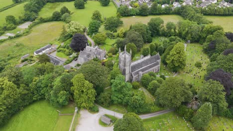 Aerial-view-of-a-scenic-gothic-church-surrounded-by-lush-greenery-and-graveyard-in-the-English-countryside