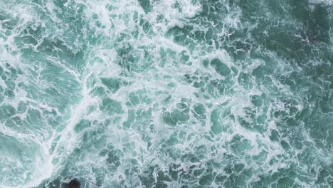 Drone-Arriba-Hacia-Abajo-Estático-De-Olas-Del-Océano-Rompiendo-Y-Agitando-Con-Agua-De-Mar-Verde,-Textura-Natural