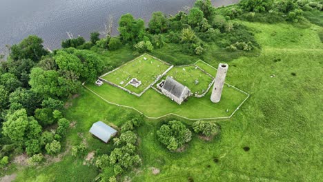 Lugares-épicos-De-Irlanda-Sitio-Monástico-Del-Río-Lough-Derg-Shannon-Desde-Arriba-En-La-Isla-Sagrada,-Importante-Sitio-Paleocristiano-Tarde-De-Verano,-Iglesia-Y-Torre-Redonda