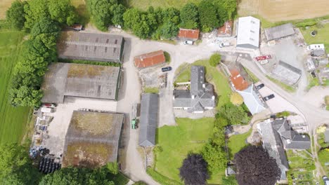 Aerial-exterior-view-of-small-farm-holdings-in-Devon-UK,-showing-buildings,-green-fields,-and-rural-surroundings