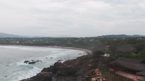 Aerial-pullback-above-homes-and-coastal-view-huts-looking-out-to-ocean-from-Puerto-Escondido-Oaxaca-Mexico