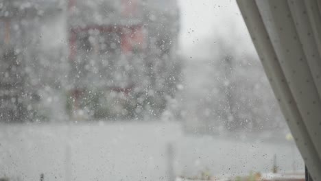 The-window-glass-is-speckled-with-water-droplets,-and-a-snowstorm-is-raging-outside