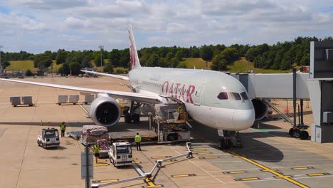 Cargo-being-unloaded-from-Qatar-Airways-airplane-on-runway-at-Hamad-International-Airport-in-Doha,-Qatar