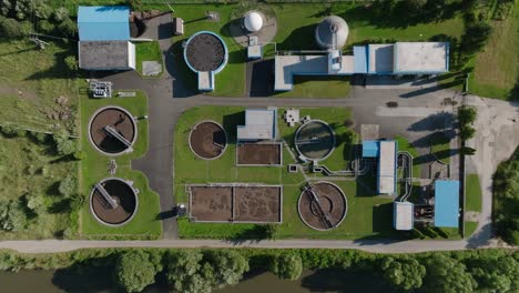 Aerial-view-of-a-modern-wastewater-treatment-plant-surrounded-by-lush-greenery,-featuring-various-tanks-and-facilities-for-processing-and-purifying-water