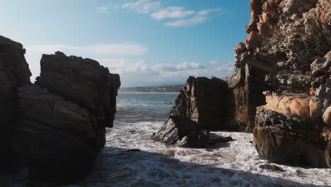 Aerial-fly-through-between-rocky-sharp-ledges-as-waves-crash-on-blocky-columns,-Puerto-Escondido-Oaxaca-Mexico