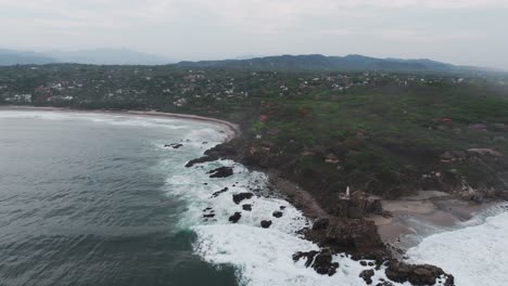 Aerial-pullback-above-Puerto-Escondido-Oaxaca-Mexico-rocky-outcropping-and-bay-on-a-stormy-day