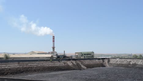 General-view-of-an-industrial-plant-with-olive-waste-and-a-smoky-chimney