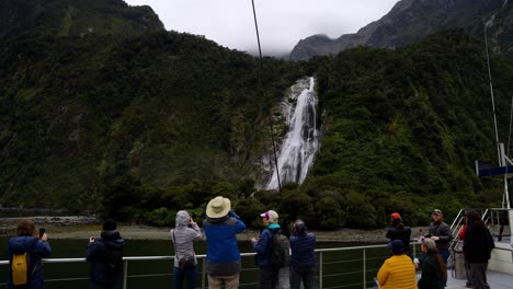 Ruhige-Aufnahme-Von-Besuchern-Auf-Einem-Boot,-Die-Die-Atemberaubende-Aussicht-Auf-Den-Wasserfall-Im-Fiordland-Nationalpark,-Neuseeland,-Genießen