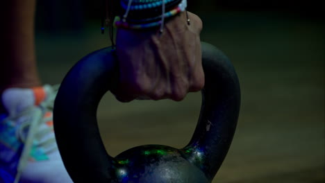 Slow-motion-close-up-of-a-kettlebell-being-grabbed-by-a-female-hand-with-red-nails-and-bracelets