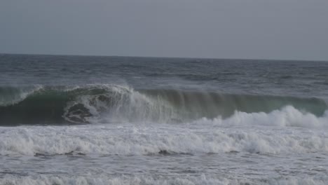 Poderosa-Ola-Rompiente-Choca-Contra-Un-Barril-Hueco-Vacío-Que-Estalla-En-Cal-En-Una-Playa-Tormentosa