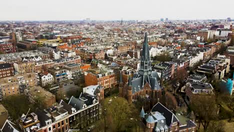 Amsterdam-cityscape-showcasing-historic-buildings-and-streets-in-daytime,-aerial-view