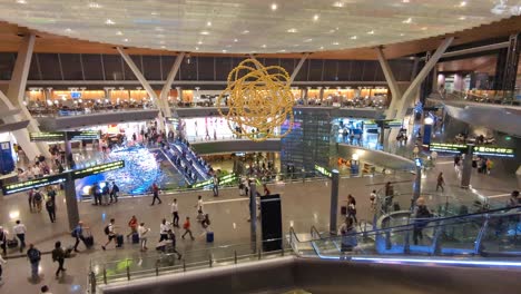 Panoramic-view-of-people-walking-around-and-escalators-at-terminal-in-Hamad-International-Airport-in-Doha,-Qatar