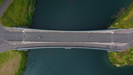 Top-still-shot-of-Triathlon-at-Dorney-lake,-triathletes-cycling-and-competing-on-the-track,-crossing-a-water-bridge