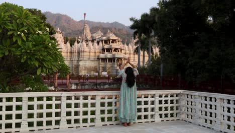 Junges-Mädchen-Betet-In-Einem-Einzigartigen-Alten-Tempel-Mit-Strahlendem-Himmel-Am-Tag.-Das-Video-Aus-Der-Rückperspektive-Wurde-Im-Ranakpur-Jain-Tempel-In-Rajasthan,-Indien,-Aufgenommen.