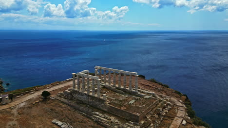 Toma-Aérea-Del-Templo-De-Poseidón-En-El-Océano-Azul-De-Grecia,-Cámara-Lenta,-Espacio-De-Copia