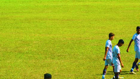 Young-football-players-warming-up-before-the-game-with-green-grass-on-the-background