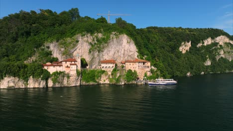 Aerial-view-of-monastery-buildings-and-boat-on-shore-of-Lake-Maggiore,-Italy