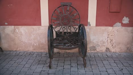 An-artistic-metal-chair-with-intricate-designs-against-an-old-wall-in-Varaždin,-Croatia