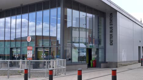 Exterior-of-Exeter-Bus-Station-with-people-entering-and-leaving-the-modern-depot,-Exeter,-Devon,-UK,-June-2024