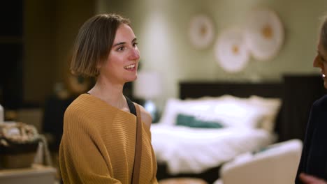 Customer-talks-to-off-screen-salesperson-walks-in-furniture-store-passing-camera