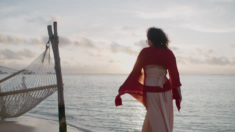 Eine-Friedliche-Szene-Mit-Einer-Brünetten-Frau,-Die-Bei-Sonnenuntergang-An-Einer-Hängematte-Am-Strand-Entlang-Läuft