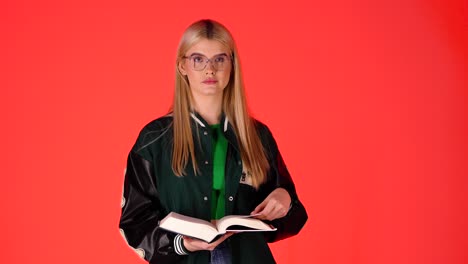 Young-Blonde-Student-Reading-a-Book,-Bored-Exhausted-and-Unmotivated,-Studio-Shot-With-Red-Background