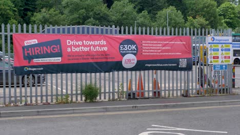 Stagecoach-hiring-banner-displayed-outside-bus-depot-promoting-job-opportunities,-Exeter,-Devon,-UK,-July-2024