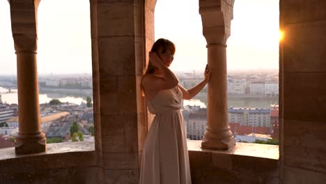 Young-woman-standing-in-a-dress-with-scenic-view-of-Budapest-and-Danube-on-a-sunny-day