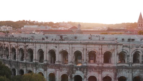 Luftaufnahme-Des-Amphitheaters-In-Nîmes,-Frankreich-Mit-Malerischer-Stadtansicht-Bei-Sonnenuntergang