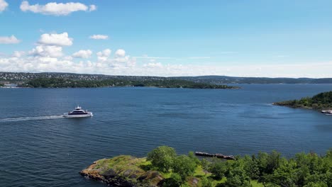 Aerial-view-of-a-boat-heading-towards-Langøyene-Island-in-Oslofjord,-Norway,-with-lush-greenery-and-calm-blue-waters