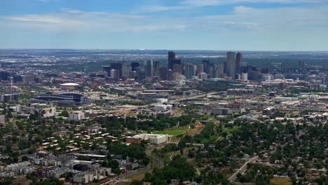 Summer-downtown-Denver-Colorado-aerial-drone-Mile-High-city-skyscrapers-neighborhood-homes-blue-skies-cloudy-6th-avenue-colfax-RTD-line-front-range-foothills-landscape-backwards-pan-up-reveal-motion