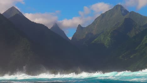 Surfing-surf-barrel-waves-Teahupoo-Tahiti-French-Polynesia-crashing-swell-on-shallow-coral-reef-South-Pacific-island-towering-mountain-peaks-ocean-waterhousing-landscape-blue-sky-super-slow-motion