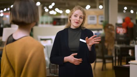 Salesperson-welcomes-customer-into-store,-asking-about-her-purchase-interests